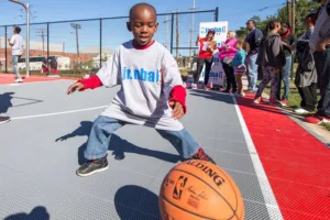 Young boy playing basketball on a Jr. NBA branded outdoor game court
