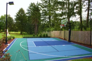 Outdoor game court with basketball hoop and an outdoor light surrounded by pine trees
