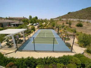 Outdoor multi-sport court at a facility with a hilly landscape and bushes
