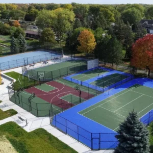 "Aerial view of a multi-sport facility featuring courts for basketball and tennis, with blue and green surfaces"