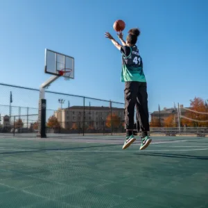 Female basketball player throwing a basketball in the air on an outdoor basketball court