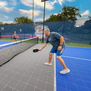 A man and kid play pickleball on an outdoor pickleball court