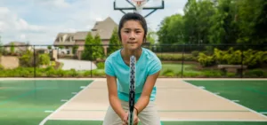 A young girl with a determined look getting ready to play tennis on an outdoor multi-sport court