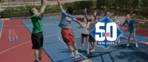 Sport Court 50th Anniversary banner with kids playing on a red and blue basketball court